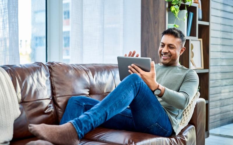 a person sitting on a couch and holding a tablet